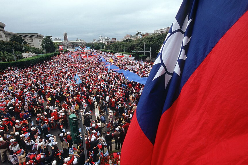 a Taiwanese flag against the backdrop of a large crowd on a large street
