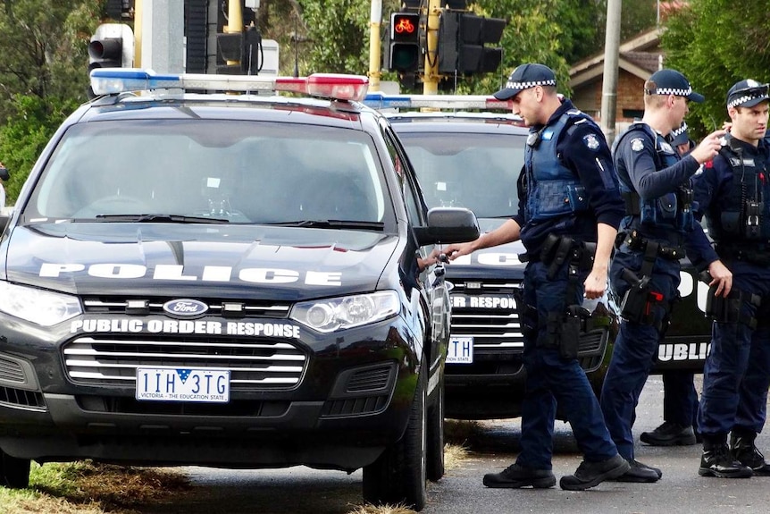 A policeman opens the door of a police car outside Brighton apartments were two people died in a siege.