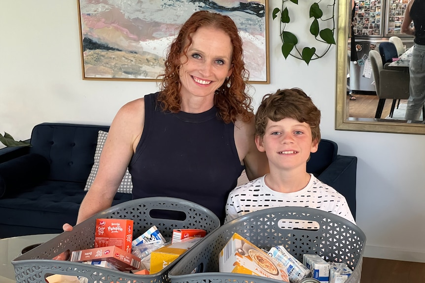 A mum and her son smile with boxes of food in front of them