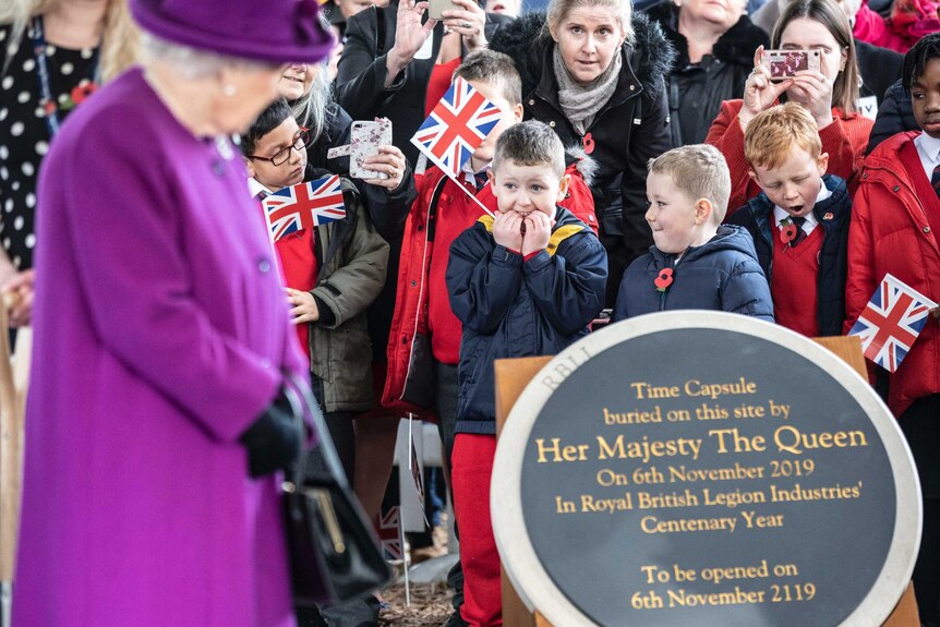 Two young boys react with glee as Queen Elizabeth II arrives to bury a time capsule.