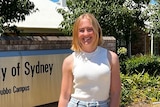 A woman stands in front of the entrance to the University of Sydney School of Rural Health