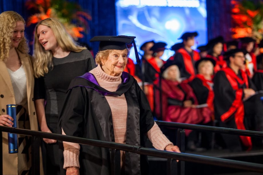 Lorna Prendergast is dressed in an academic gown and hat as she walks from the stage with her degree.