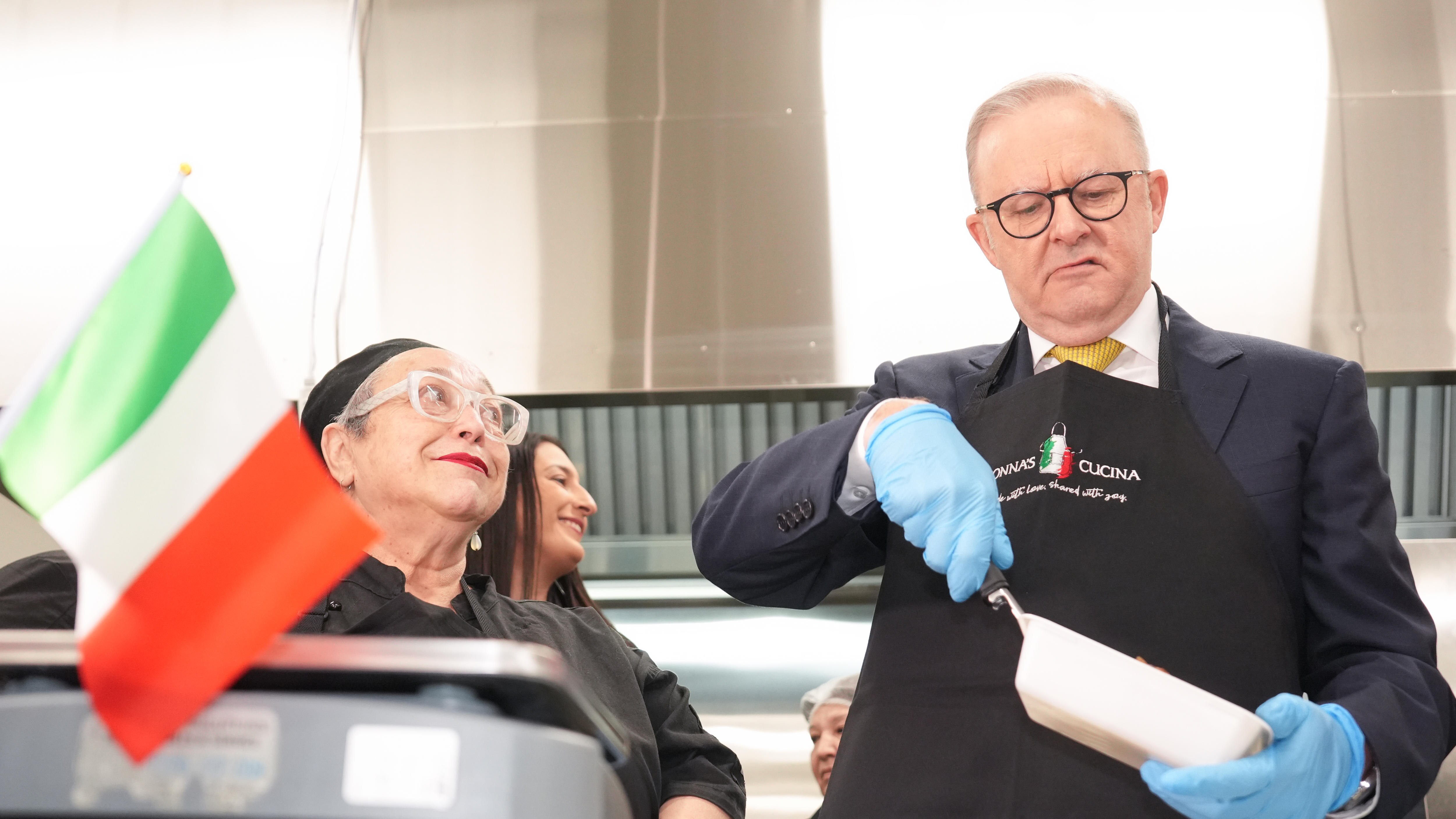 Albanese with gloves on cooks, Italian flag in foreground 
