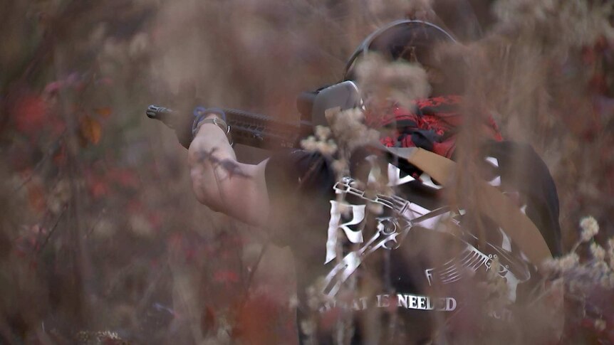 A member of Redneck Revolt aims at a target at a gun range.