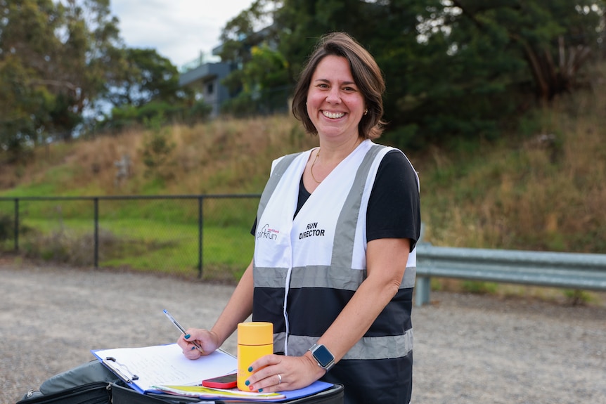 Miranda Davies in a vest that says run director standings at a table with a note book and pen. 