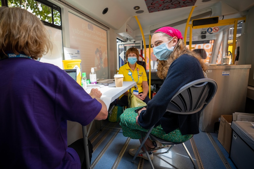 A vaccine recipient chats with medical stuff inside a mobile vaccination bus in London.