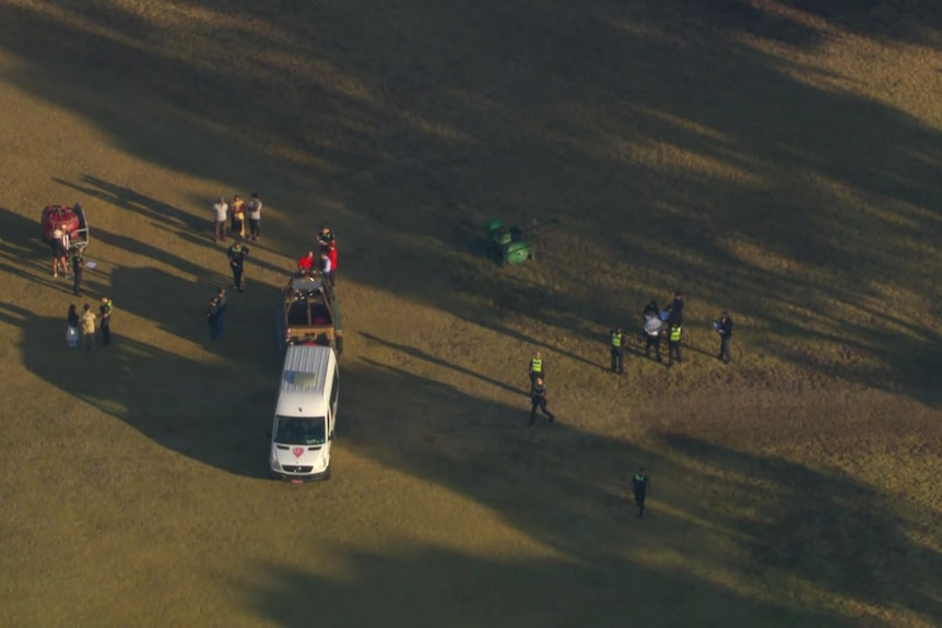 A hot air balloon landed in an oval with an ambulance