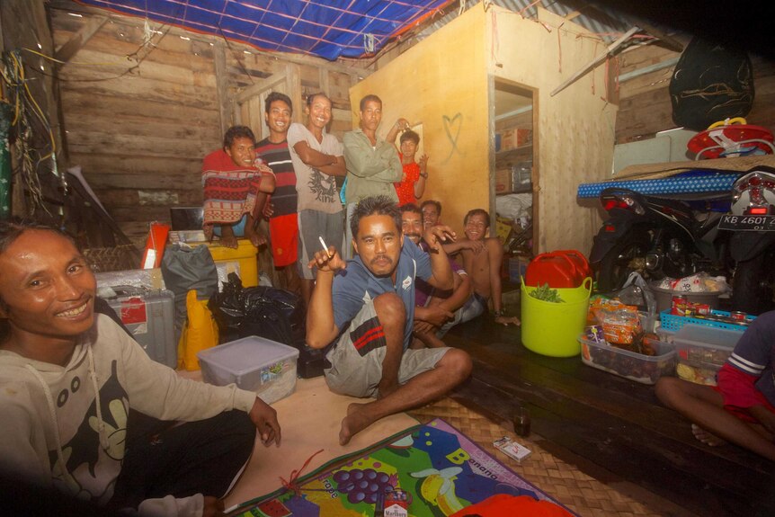 A group of Indonesian men joke around inside a house.