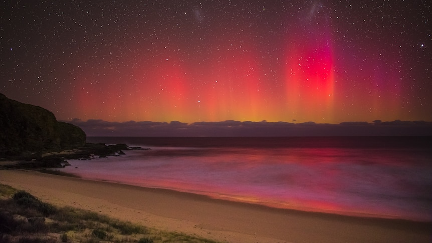 Red aurora lights over a beach in the Bass Coast at night