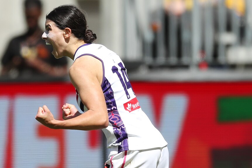 A Fremantle AFLW player pumps both her fists as she celebrates a goal.