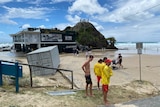 Three lifesavers and other people look at the high tide at Currumbin surf cub. 