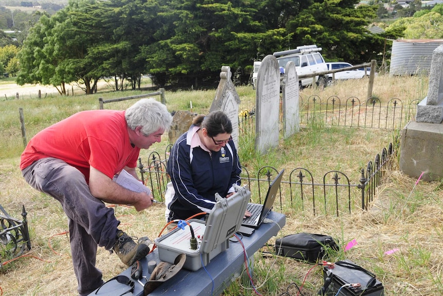 two people at computers in a graveyard