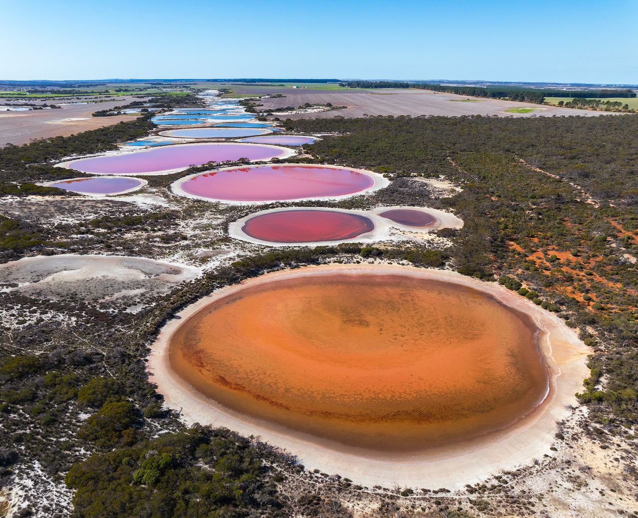 Uma foto aérea de um lago laranja, rosa, roxo e azul.