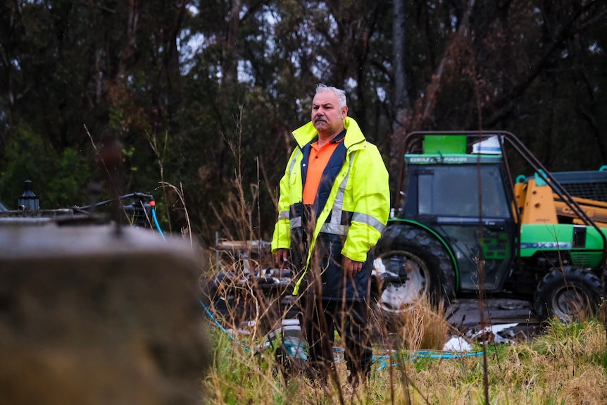 A man in green high vis jacket stands in the bush