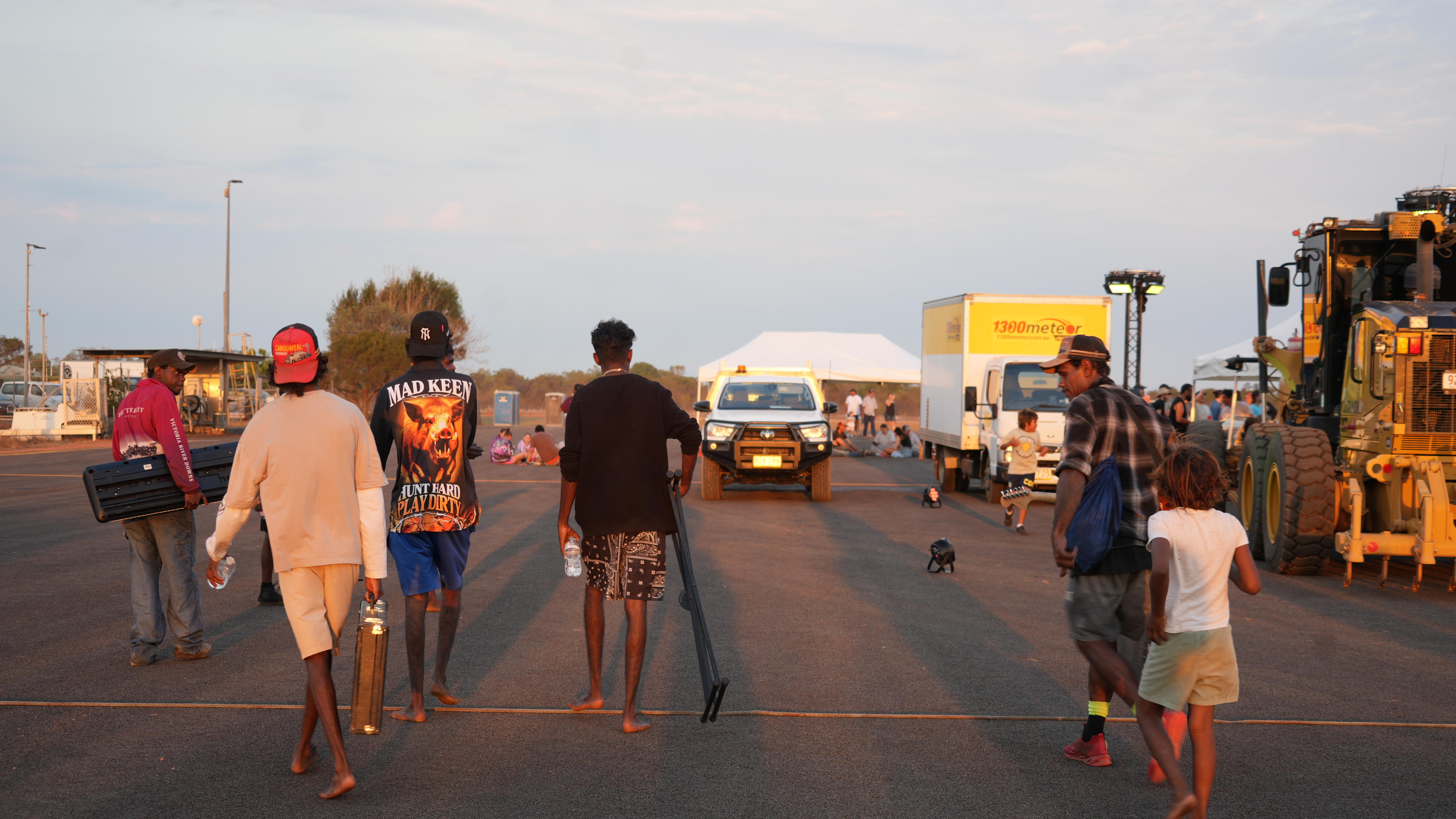 A group of young men pictured from the rear walking on a an outback street