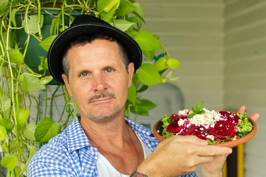 A man stands holding a dragon fruit salad.