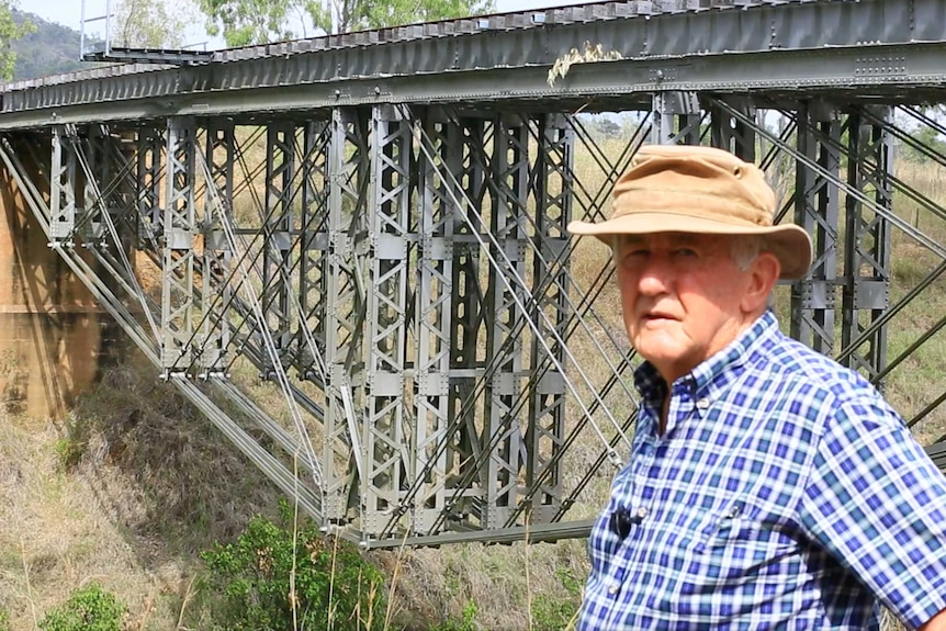 Man stands in front of iron bridge