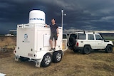 Dr Joshua Soderholm stands on a trailer loaded with weather instruments.