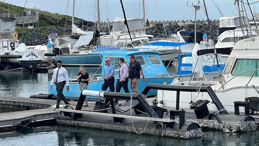 Five detectives walking on a small jetty.