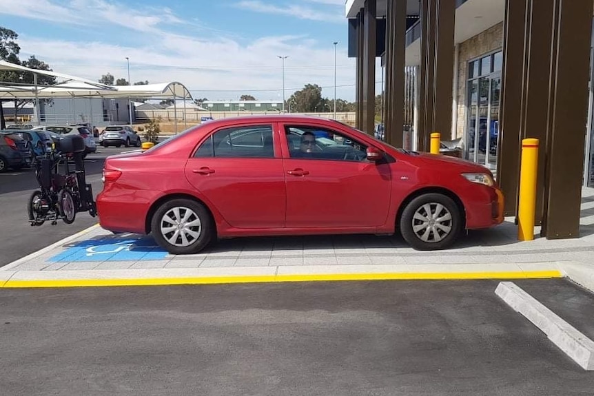 Small red car parked in disabled spot