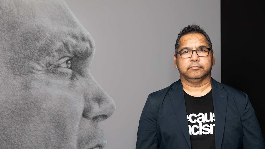 The Aboriginal Australian artist Vernon Ah Kee standing in front of one of his large scale drawings