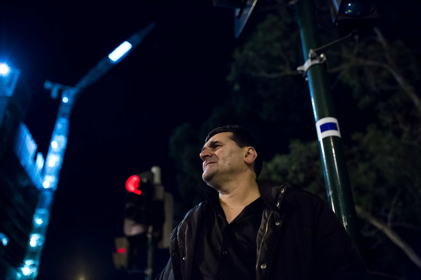 A man pauses at a set of lights