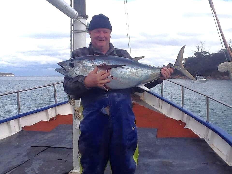 A man with a fish on board a boat.