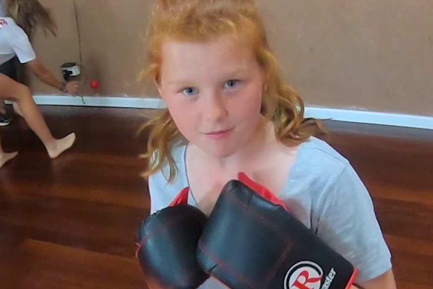 A teenage girl wearing boxing gloves