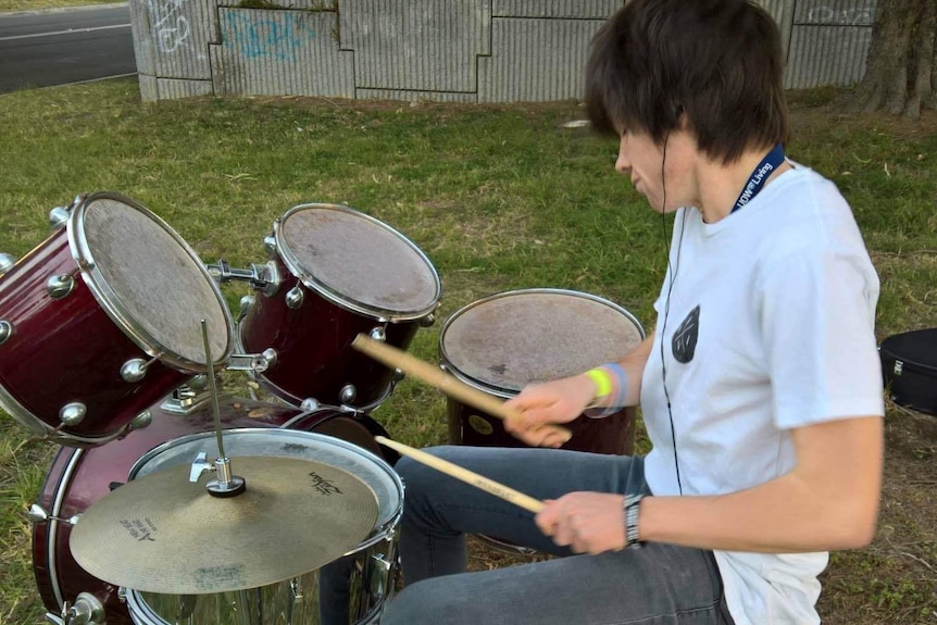 A teenage boy plays his drumkit in a Wollongong park
