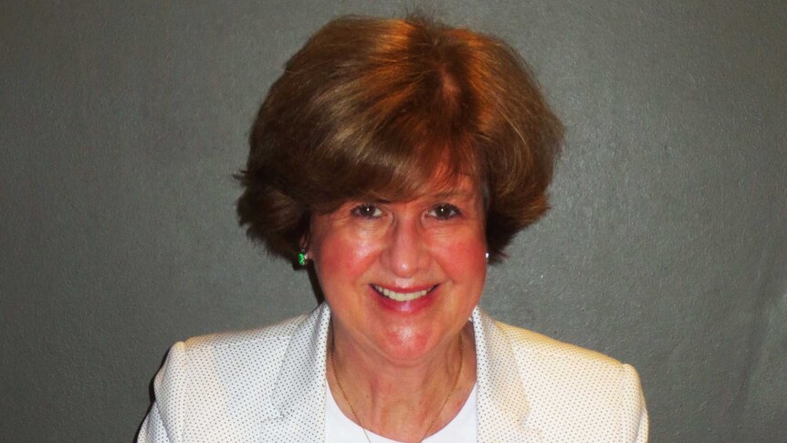 Gwen Woodford smiling while siting at a dining table.