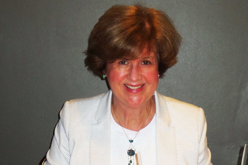 Gwen Woodford smiling while siting at a dining table.