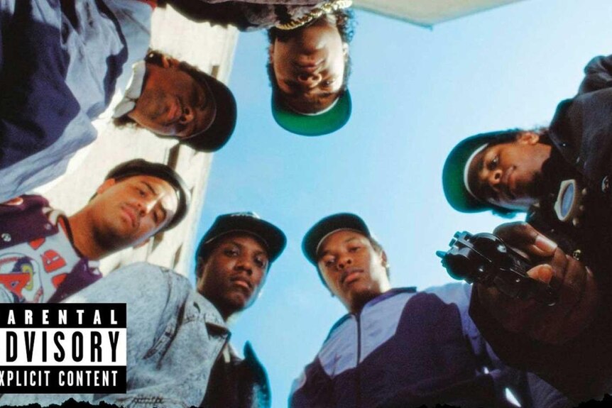 A hip hop group looks down at a camera.