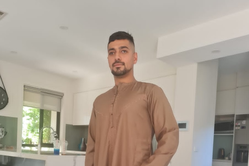 A photo of Aymen wearing a light brown Islamic garment for men.