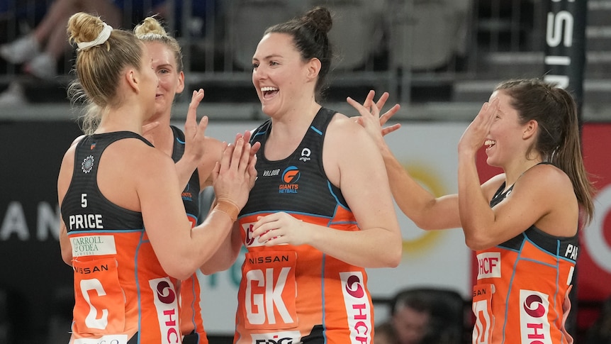 A group of Giants Super Netball players congratulate each other.