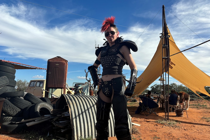A person dressed in leather with a red mohawk. 