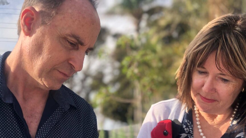 A man and a woman, wearing red poppies for remembrance