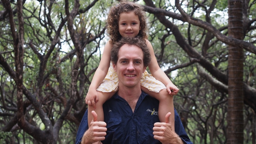 A daughter smiles as she sits on her dad's shoulders on Fraser Island.