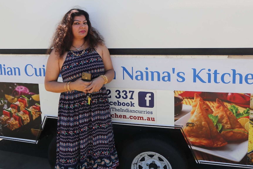 A woman stands in front of a closed food van