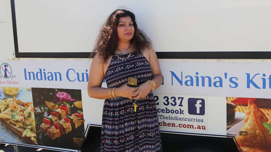 A woman stands in front of a closed food van