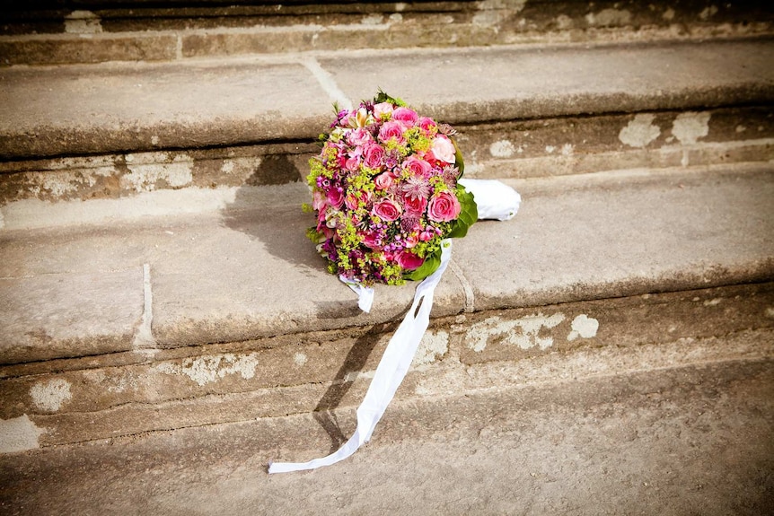 A bunch of flowers sits on stone stairs.