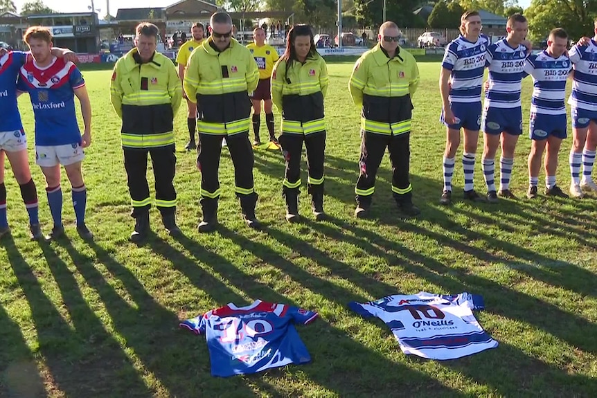 two teams embrace with emergency responders on a field as two number ten jerseys are placed on the floor