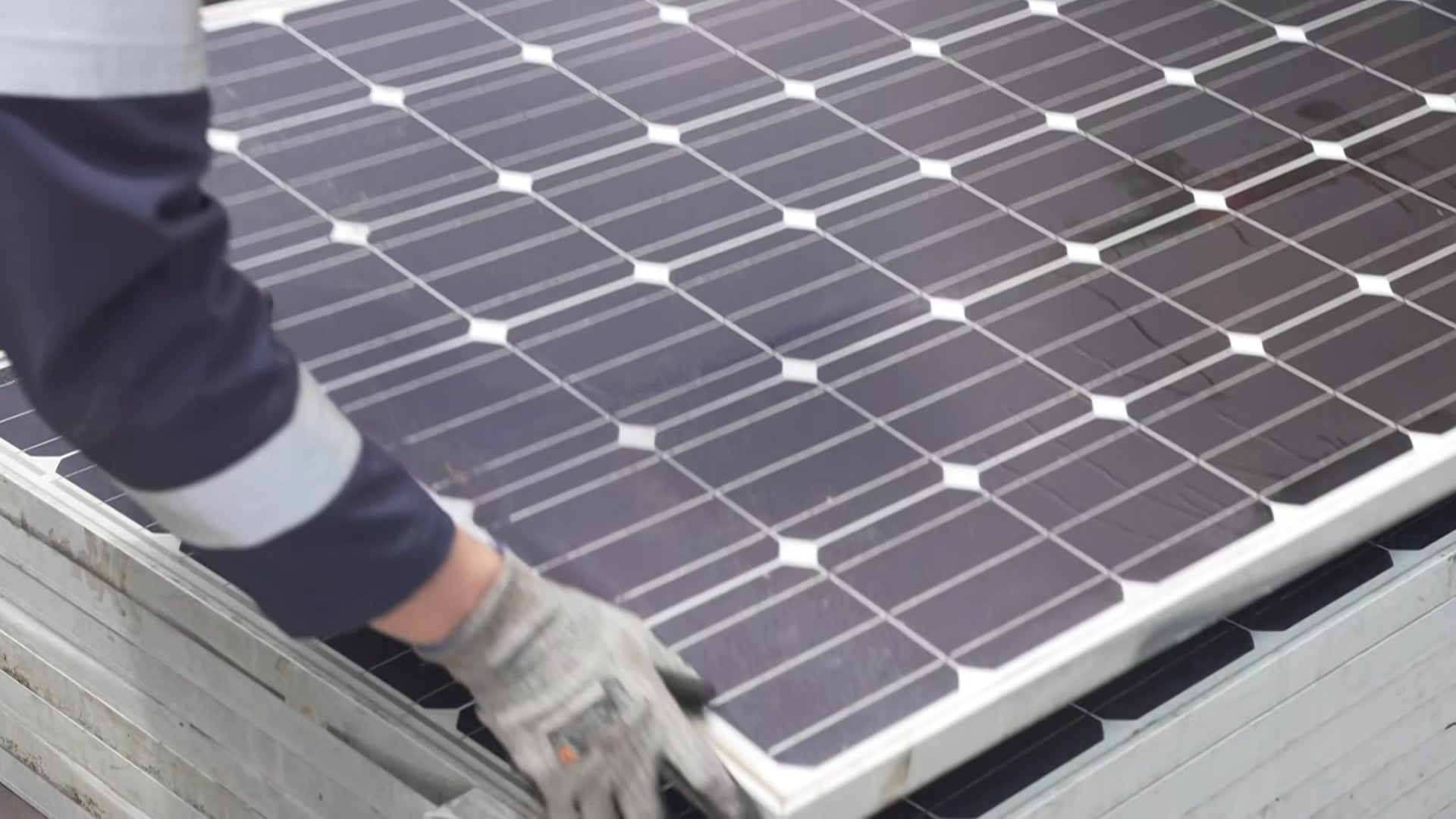 a close up photo of a solar panel with a man lifting one corner of it.