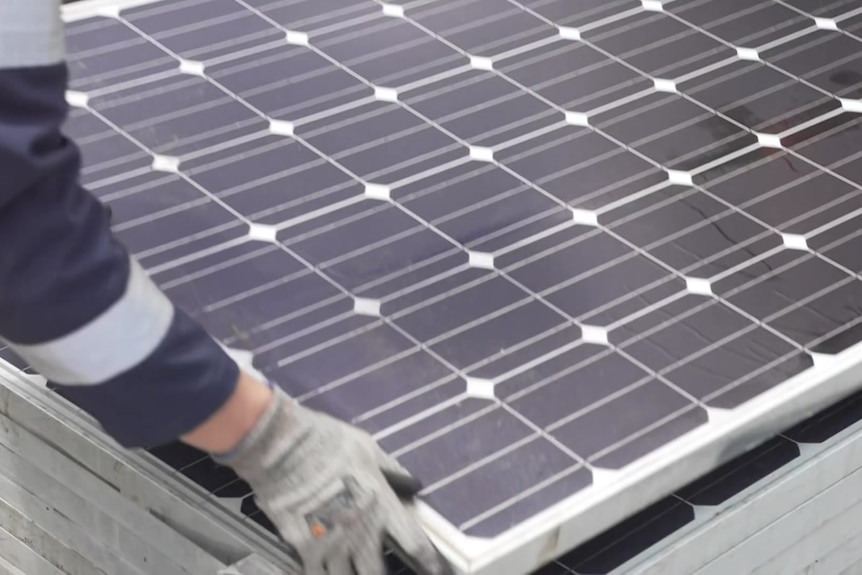 a close up photo of a solar panel with a person lifting one corner of it.