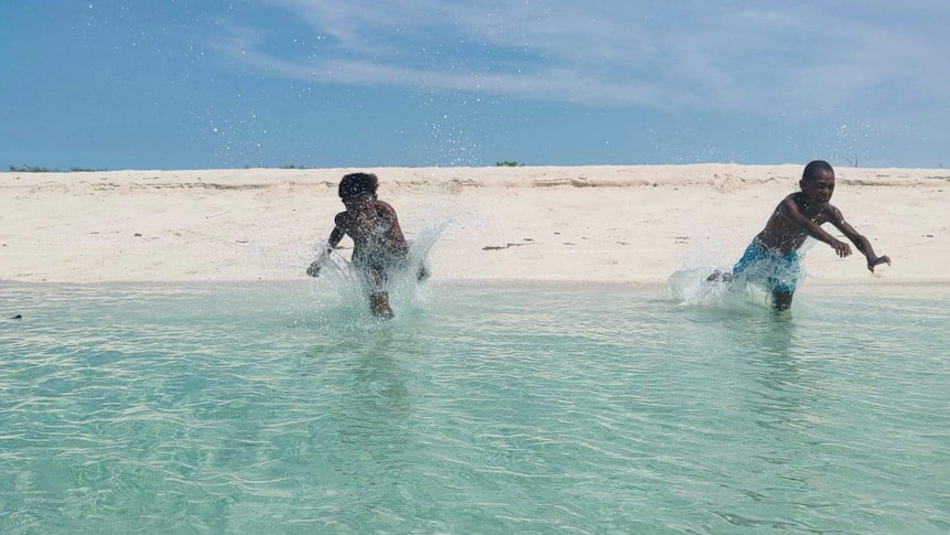 Two Torres Strait Islander children diving into clear blue water.