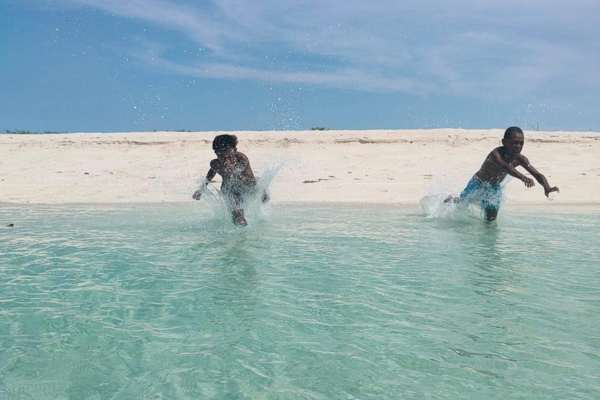 Two Torres Strait Islander children diving into clear blue water.