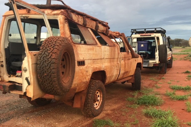 A 4WD with mud on it. Another vehicle is parked in front.