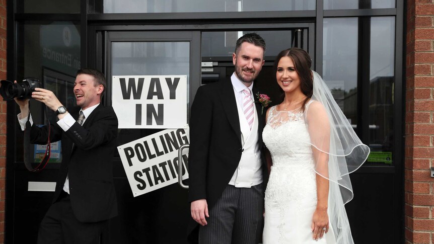 Sorcha Eastwood and her husband Dale Shirlow post in their wedding attire outside a polling station.