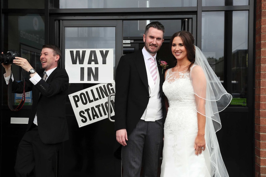 Sorcha Eastwood and her husband Dale Shirlow post in their wedding attire outside a polling station.