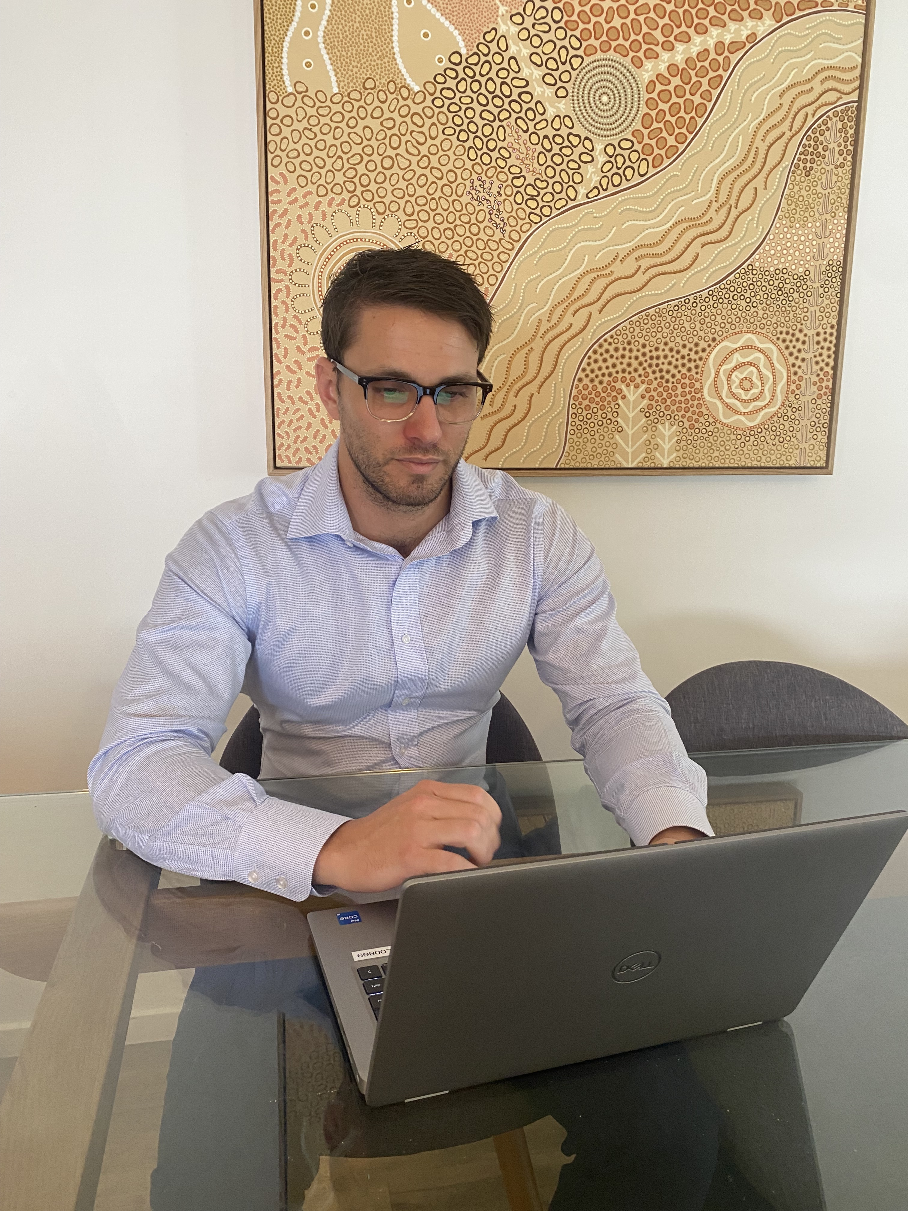 a man at a computer with indigenous artwork behind him