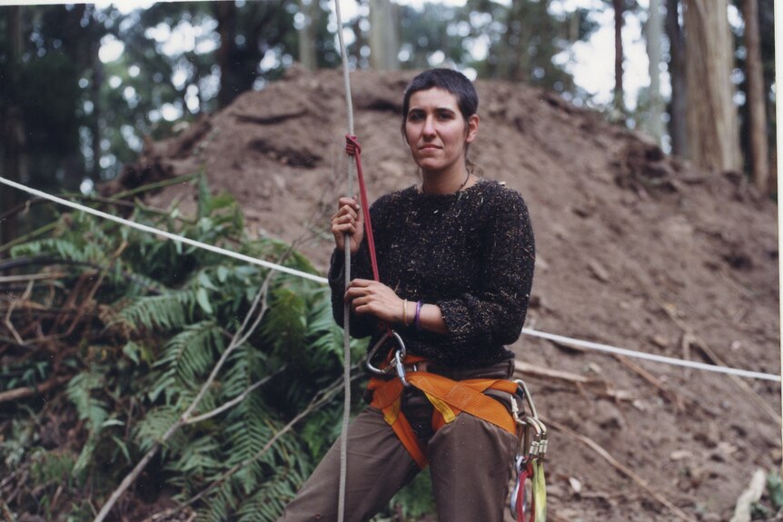 A woman ready to abseil up a tree.
